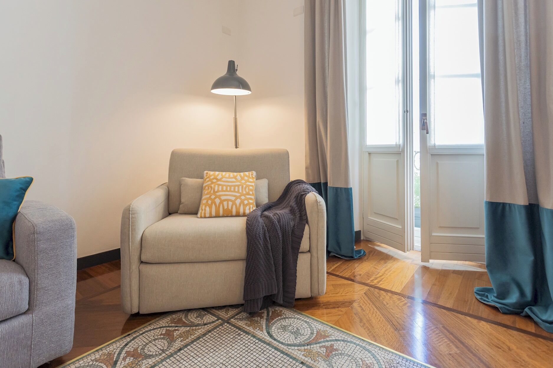 A cozy living room with a sofa, a patterned rug, and a floor lamp.