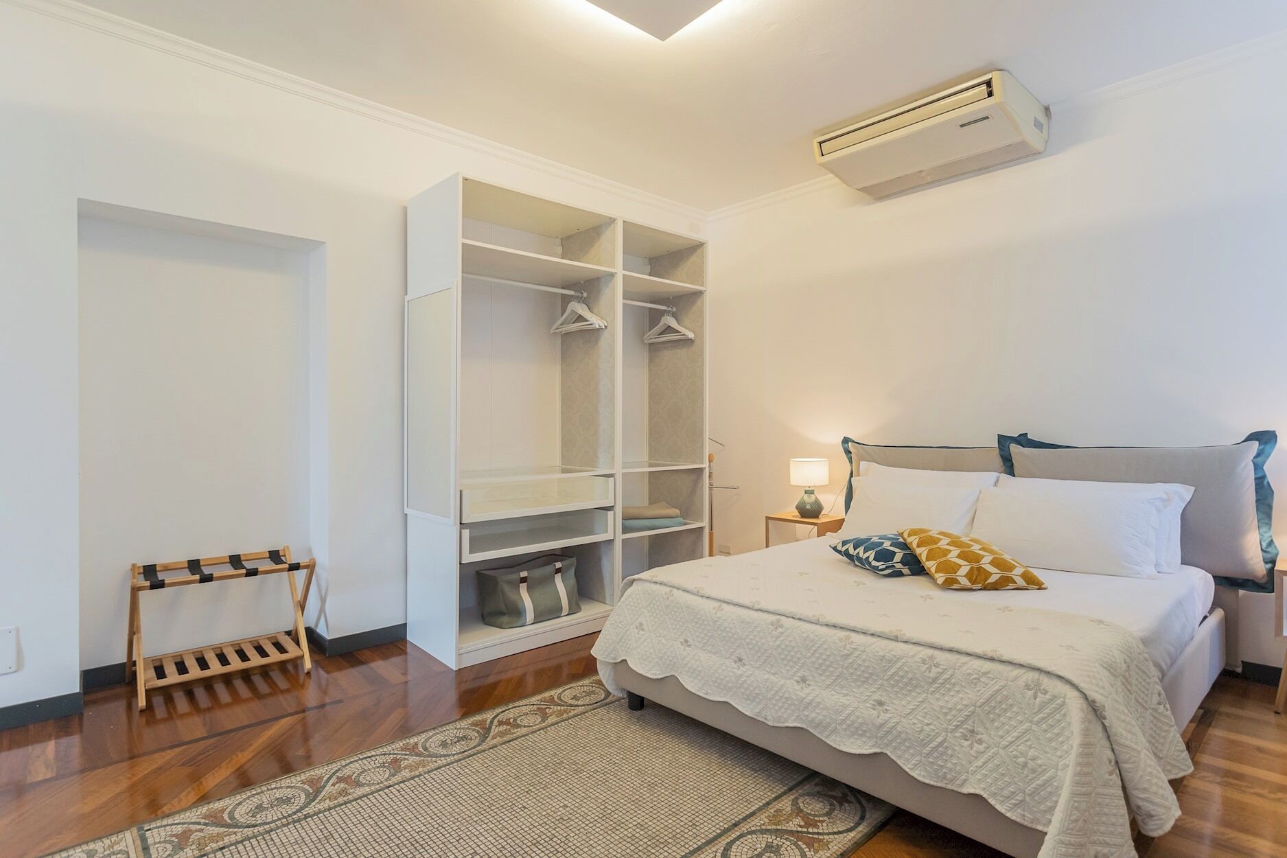Une chambre à coucher comprenant un lit, une armoire, une table de chevet et un appareil de climatisation.