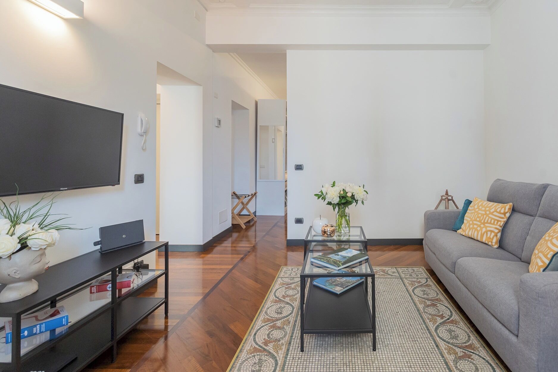 A modern living room with a flat-screen TV, a sofa, a coffee table, and a bookshelf.