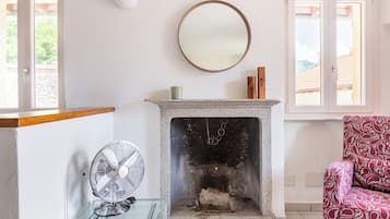 Una habitación con chimenea, un ventilador y una silla.