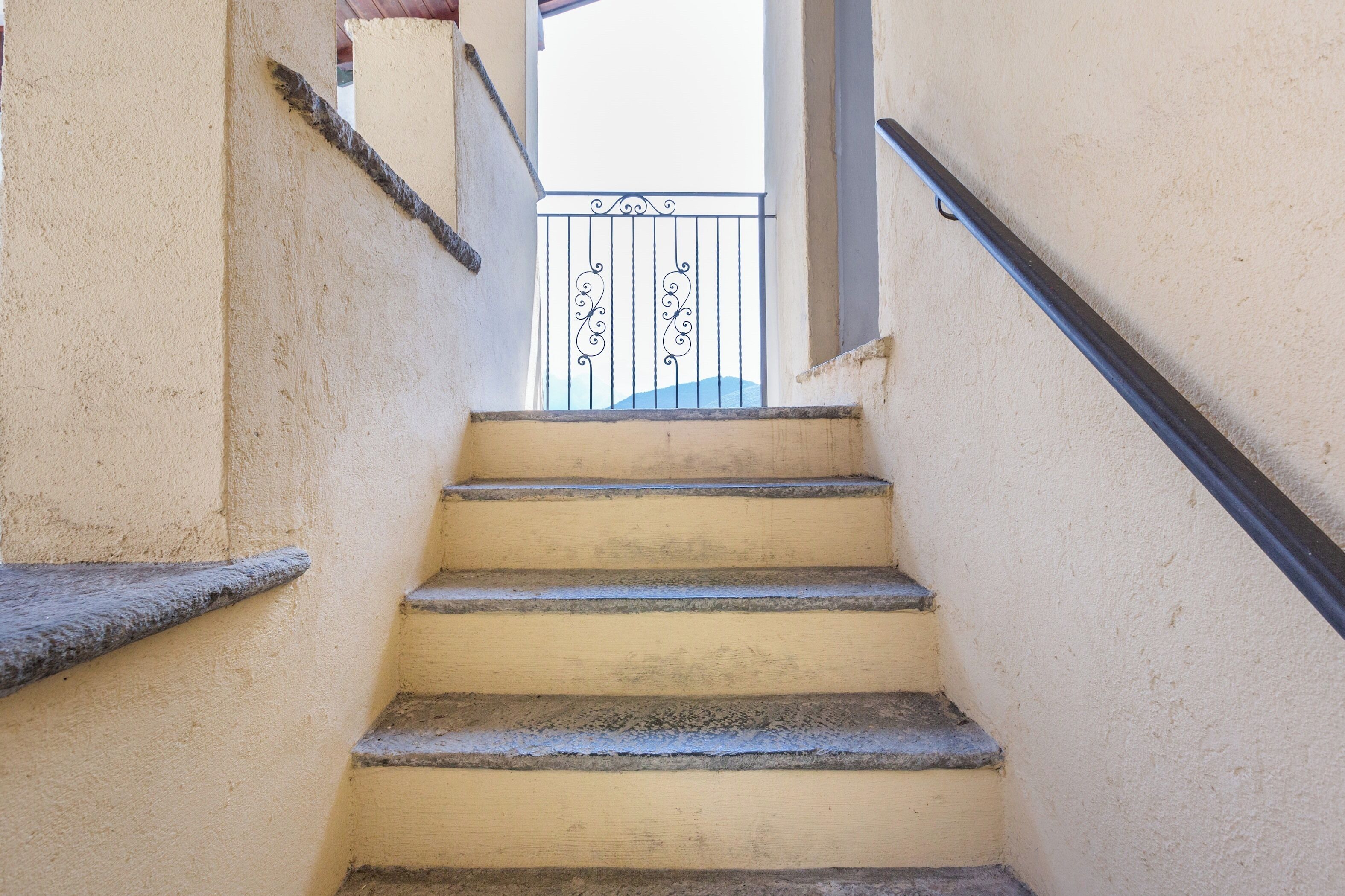 A set of stone steps leading up to a balcony with wrought iron railings.