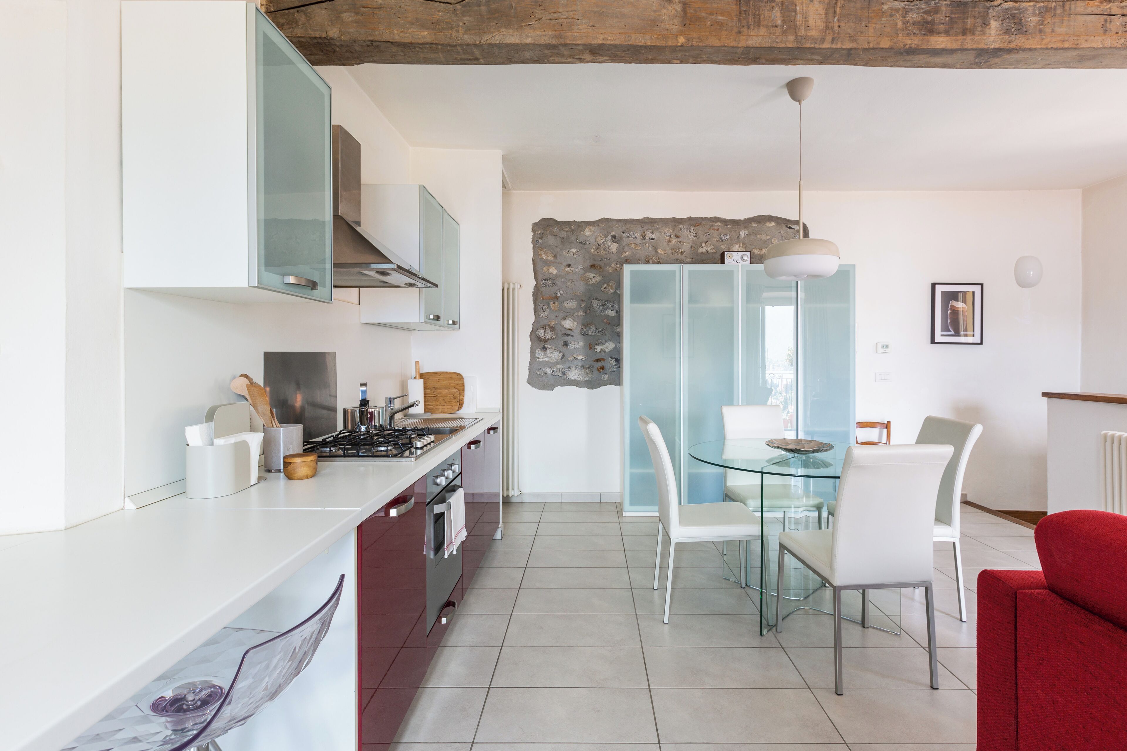 A modern kitchen with white cabinets, a gas stove, and a dining area with a glass table and white chairs.