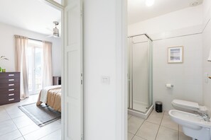A hotel room with a bed, a dresser, a bathroom with a shower, toilet, and sink.