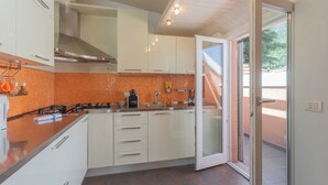Une cuisine moderne avec des meubles blancs, un dosseret carrelé orange et une cuisinière à gaz.