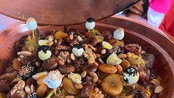 Un pot en argile traditionnel rempli d’un ragoût, garni de noix, de graines et d’œufs.