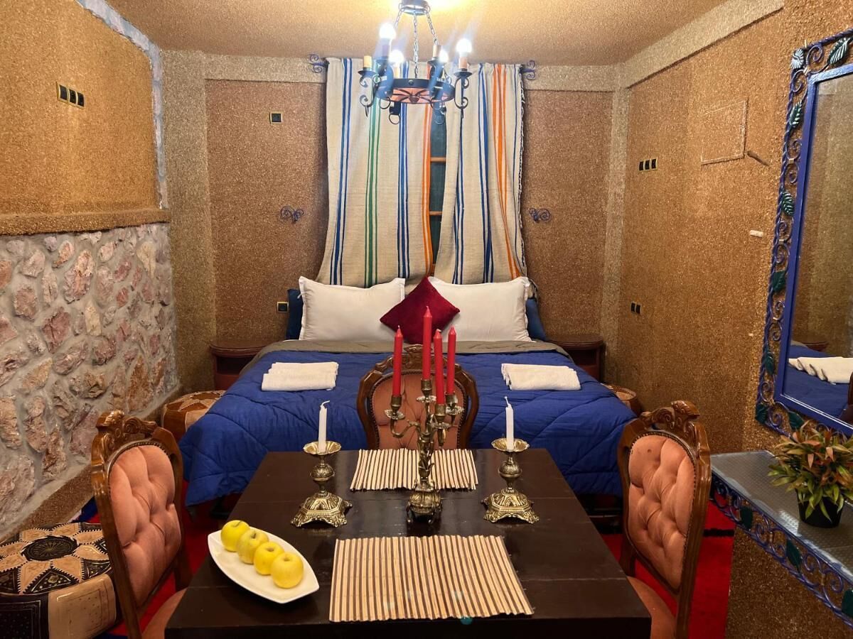 A hotel room with a bed, a dining table with candles, and a chandelier.