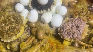 A traditional dish with various ingredients including fish, eggs, olives, and a sauce.