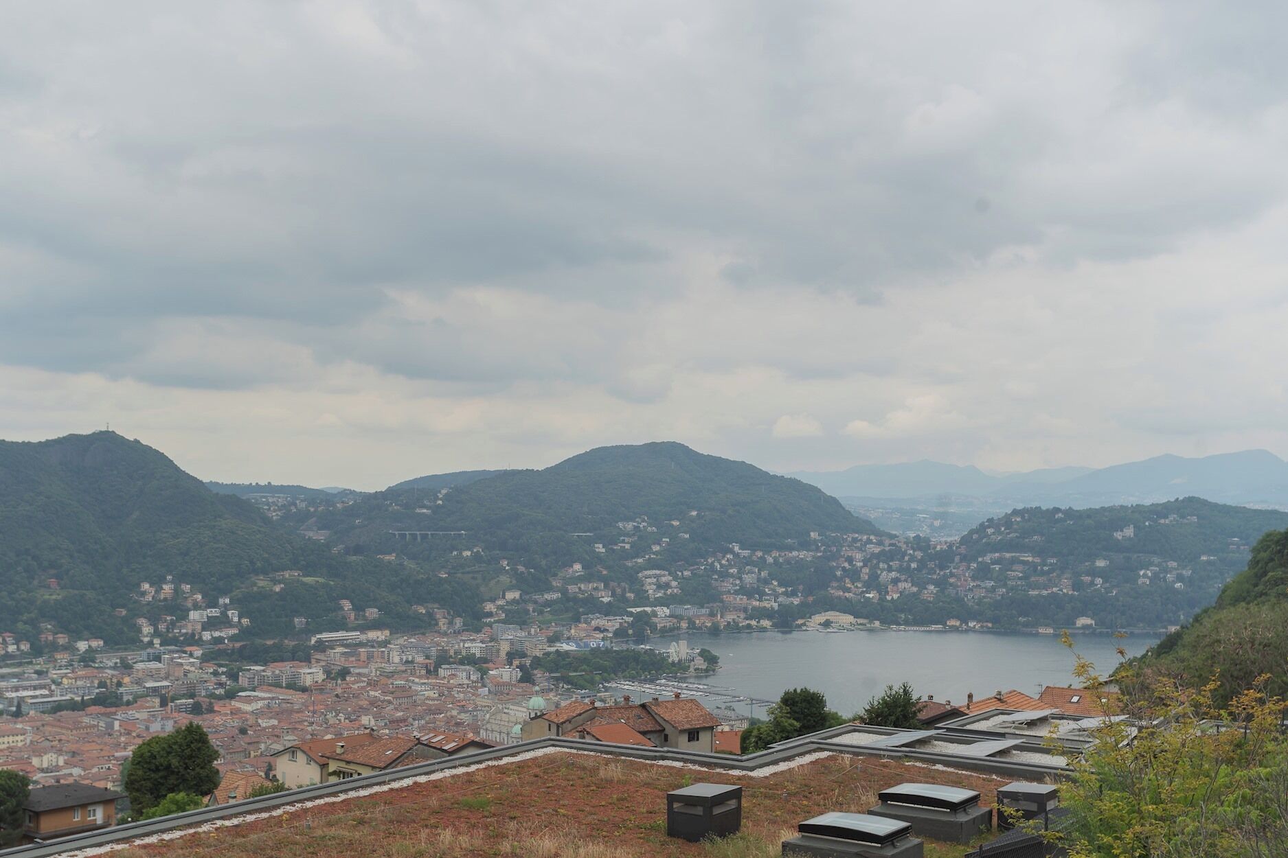 A panoramic view of a coastal city with a river, mountains, and a bridge.