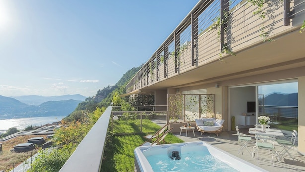 Un hotel moderno con piscina en la azotea, mobiliario exterior y vistas panorámicas a la montaña.