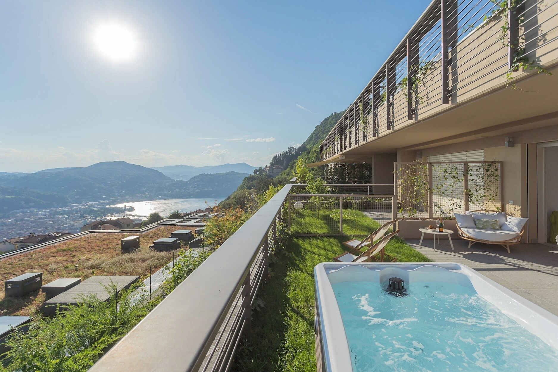 A modern outdoor swimming pool with a view of a mountainous landscape and a distant body of water.