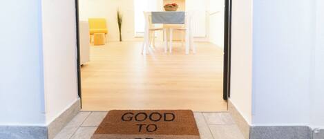 A hallway with a doormat that reads "GOOD TO BE HOME."