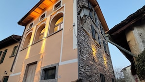 A multi-story building with a stone facade, arched windows, and a flat roof. - Mezzegra Apartments by Rent all Como (Tremezzina)