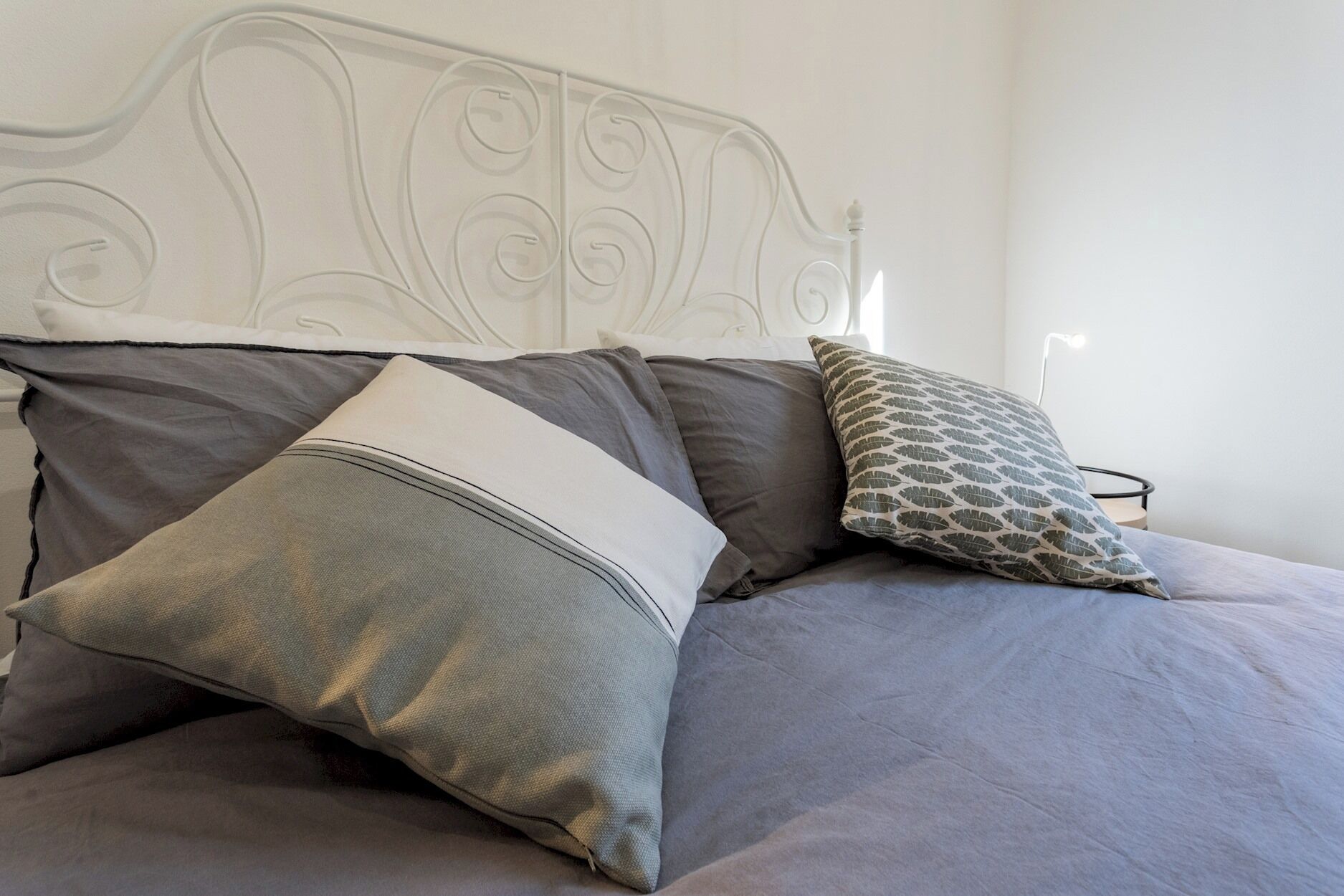 A bed with grey bedding and decorative pillows.