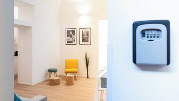 A modern living room with a yellow chair, wooden stools, and framed pictures on the wall.