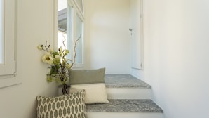 A staircase with a white wall, a vase with flowers, and patterned cushions. - Mezzegra Apartments by Rent all Como (Tremezzina)