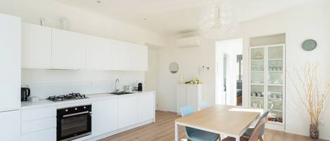 A modern kitchen with white cabinetry, a wooden dining table, and chairs.