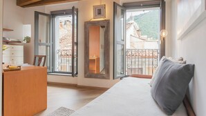 A cozy room with a wooden ceiling, a white sofa, a dining table with a glass, and a view of a building with a dome through open doors.
