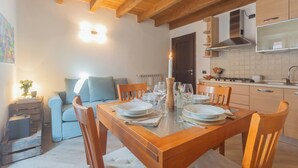 A cozy dining area with a wooden table set for four, a sofa, and a kitchen in the background.
