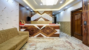 Een modern ingerichte receptie, met een houten receptiebalie, een comfortabele bank en een kroonluchter.