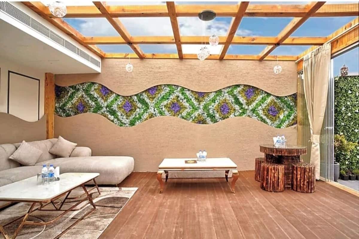 Une pièce baignée de lumière, avec un plafond en bois, un canapé, une table basse et une table ronde en bois, entourée de tabourets.