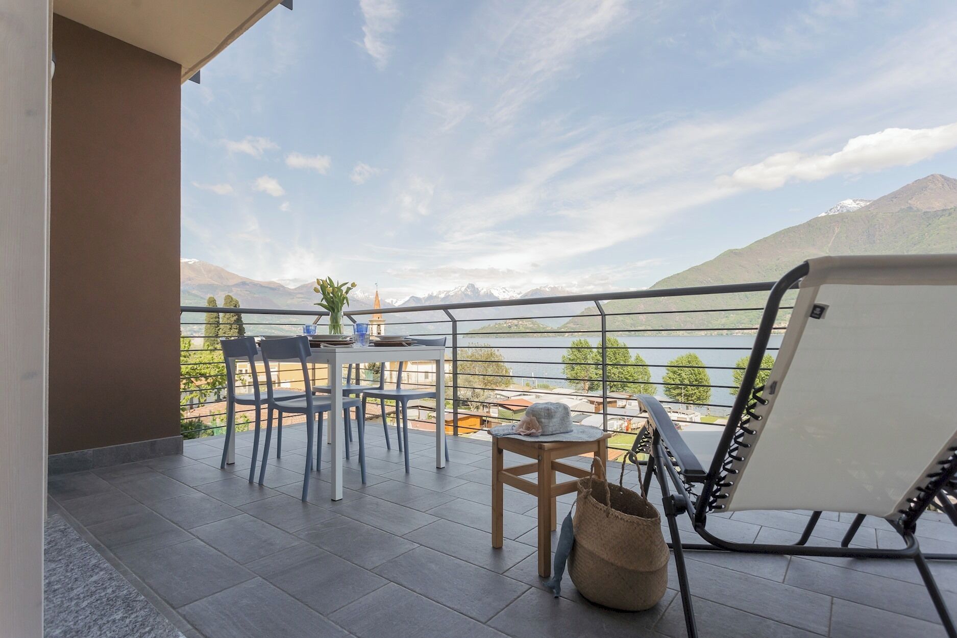 Un balcon avec une table et des chaises, donnant sur un lac et des montagnes.