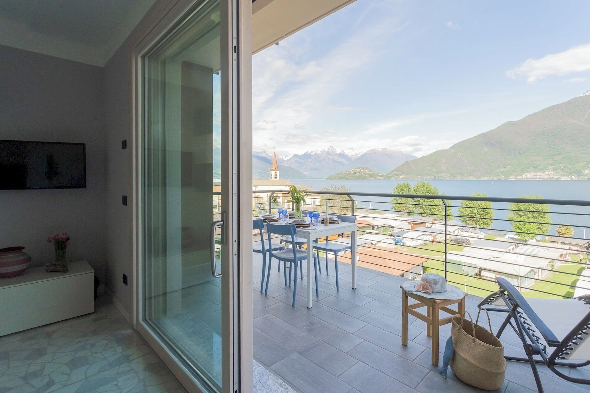 A balcony with a table set for dining, overlooking a lake and mountains.