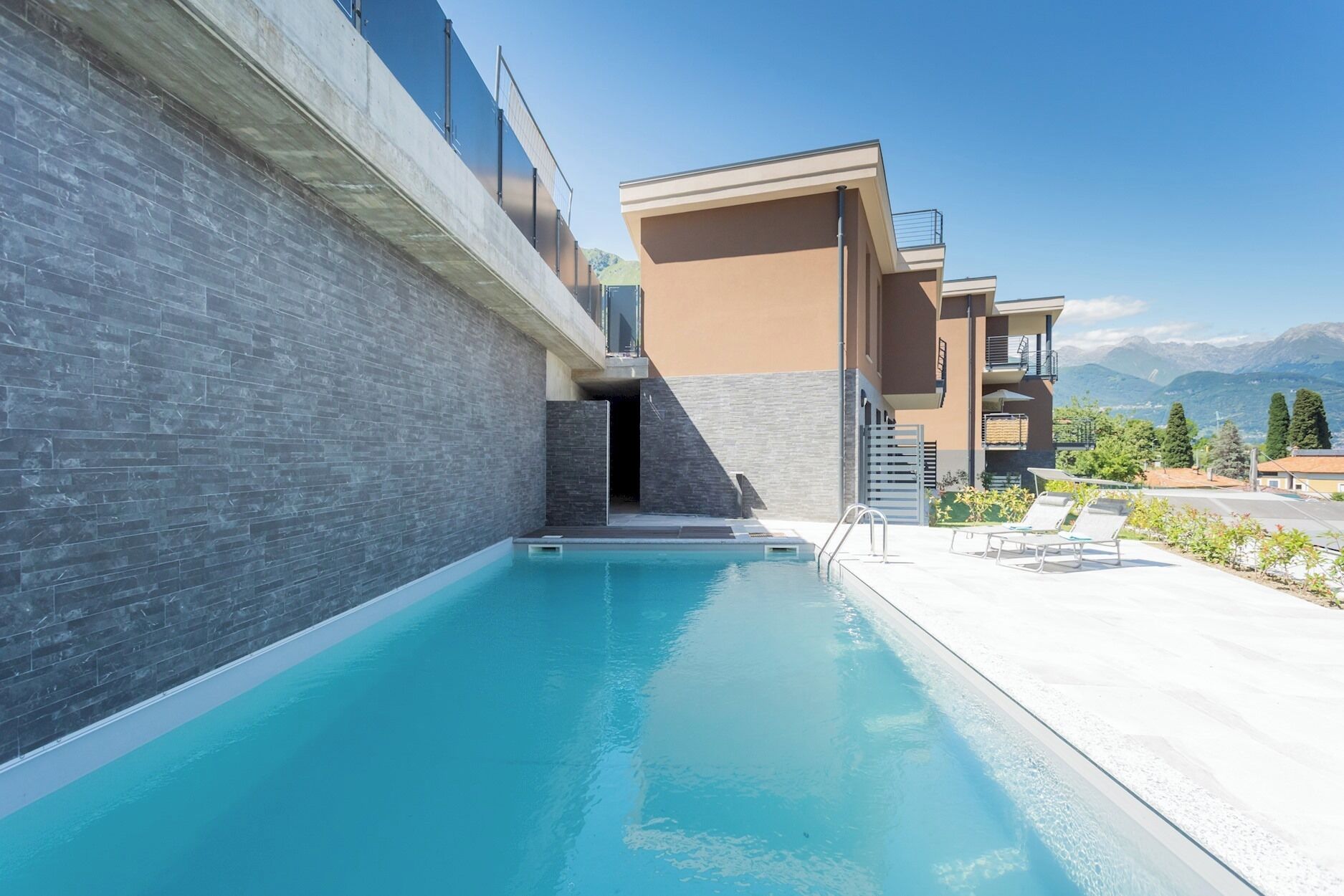 Un área de piscina moderna con una vista despejada de las montañas al fondo.