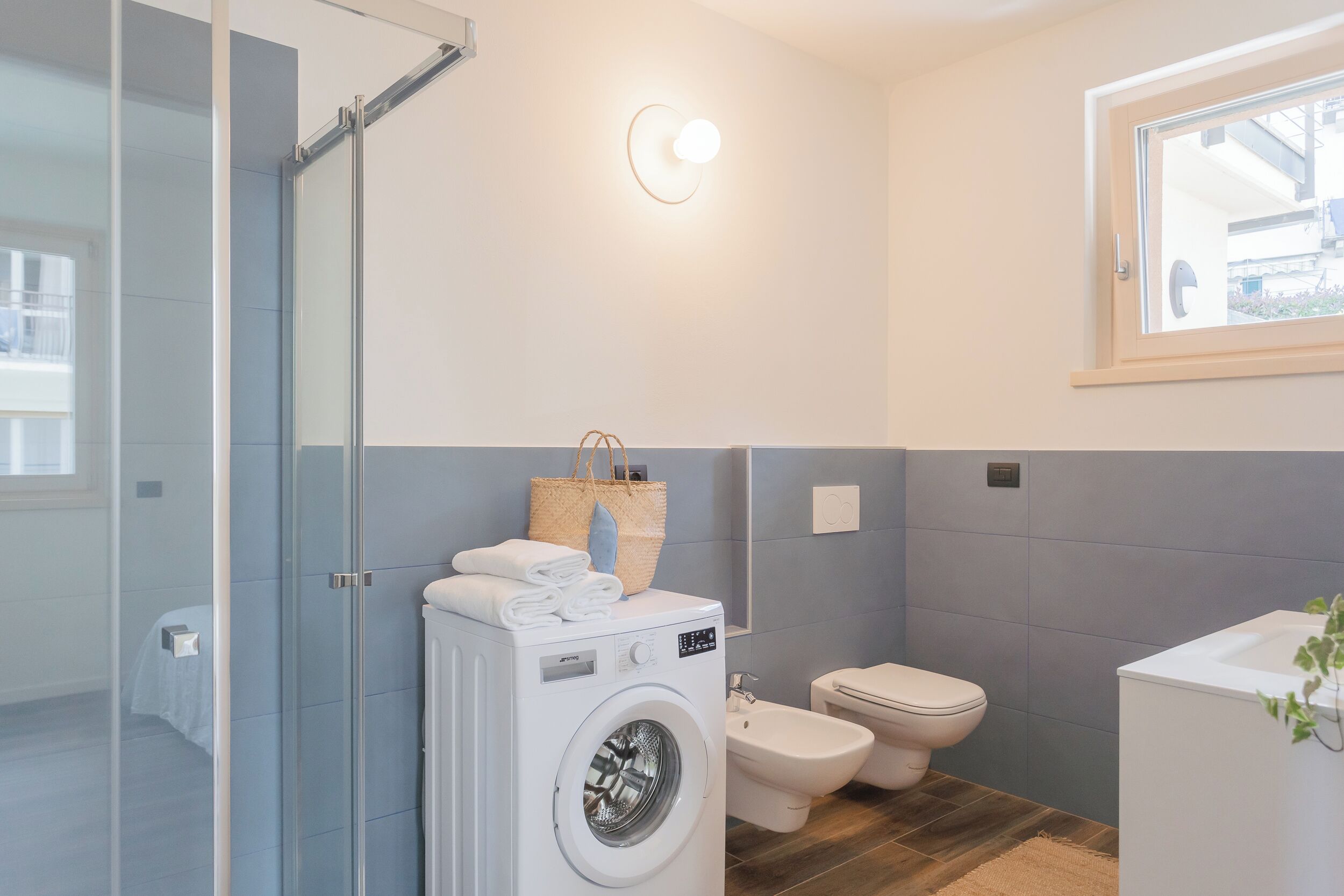 Une salle de bain moderne dotée d’une douche à parois de verre, d’un lave-linge, d’un bidet et d’un lavabo.
