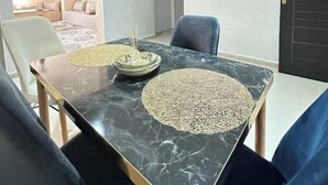 Ein Essbereich mit einem Marmortisch, zwei Stühlen und einer schwarzen Tür.