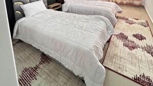 Ein Schlafzimmer mit zwei Betten, einer dunklen Wand und einem gemusterten Teppich.