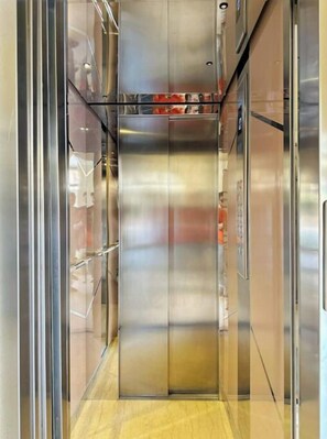 Un ascensor moderno con paredes metálicas y suelo reflectante.