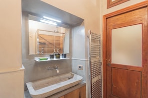 A bathroom with a stone sink, a mirror, and a wooden door. - Pantero Apartment by Rent all Como (Como)