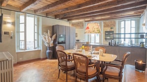 A dining area with wooden chairs, a table set for four, and a large window with a view. - Pantero Apartment by Rent all Como (Como)