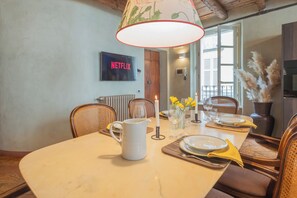 A dining area with a table set for four, a white pitcher, candles, and yellow flowers. - Pantero Apartment by Rent all Como (Como)