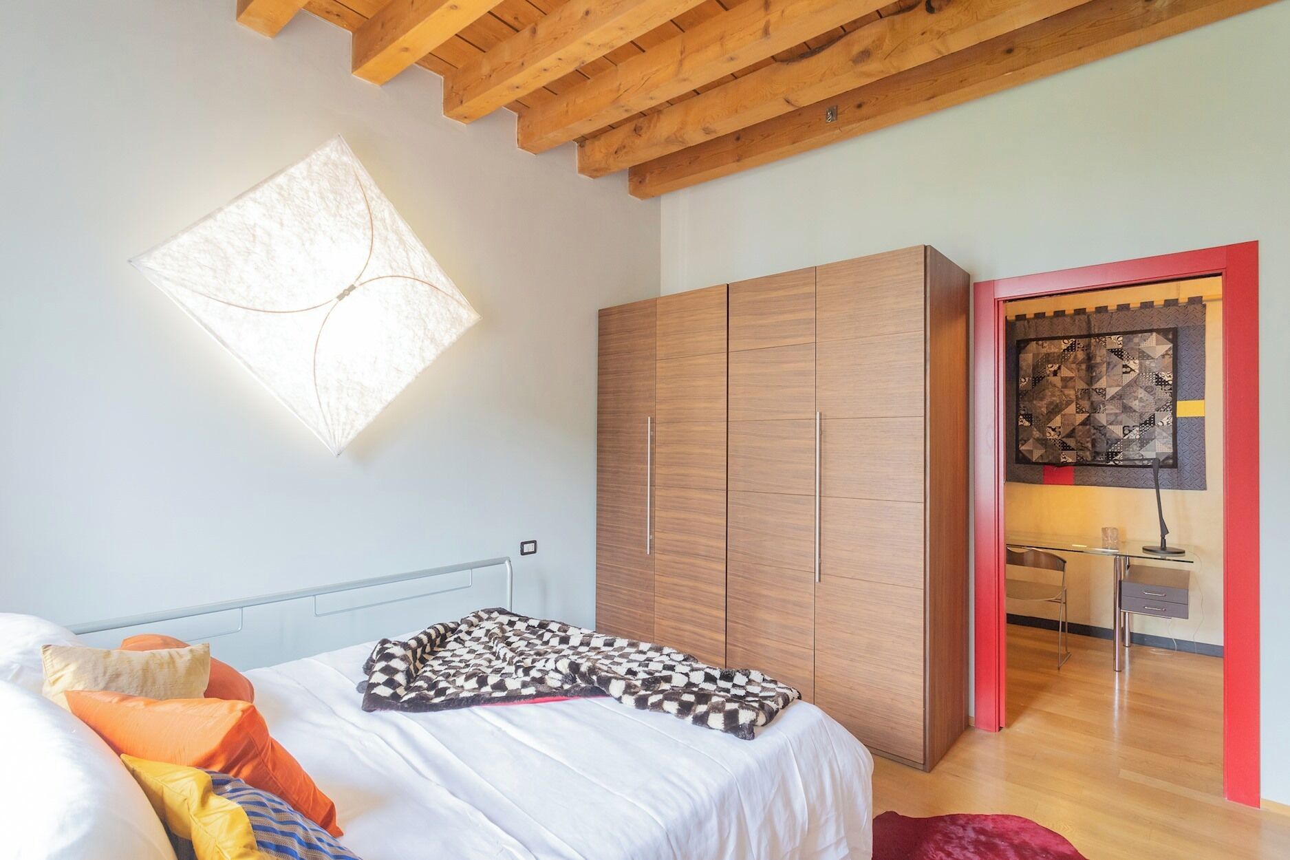 A bedroom with a bed, a wardrobe, and a unique wall-mounted light fixture.