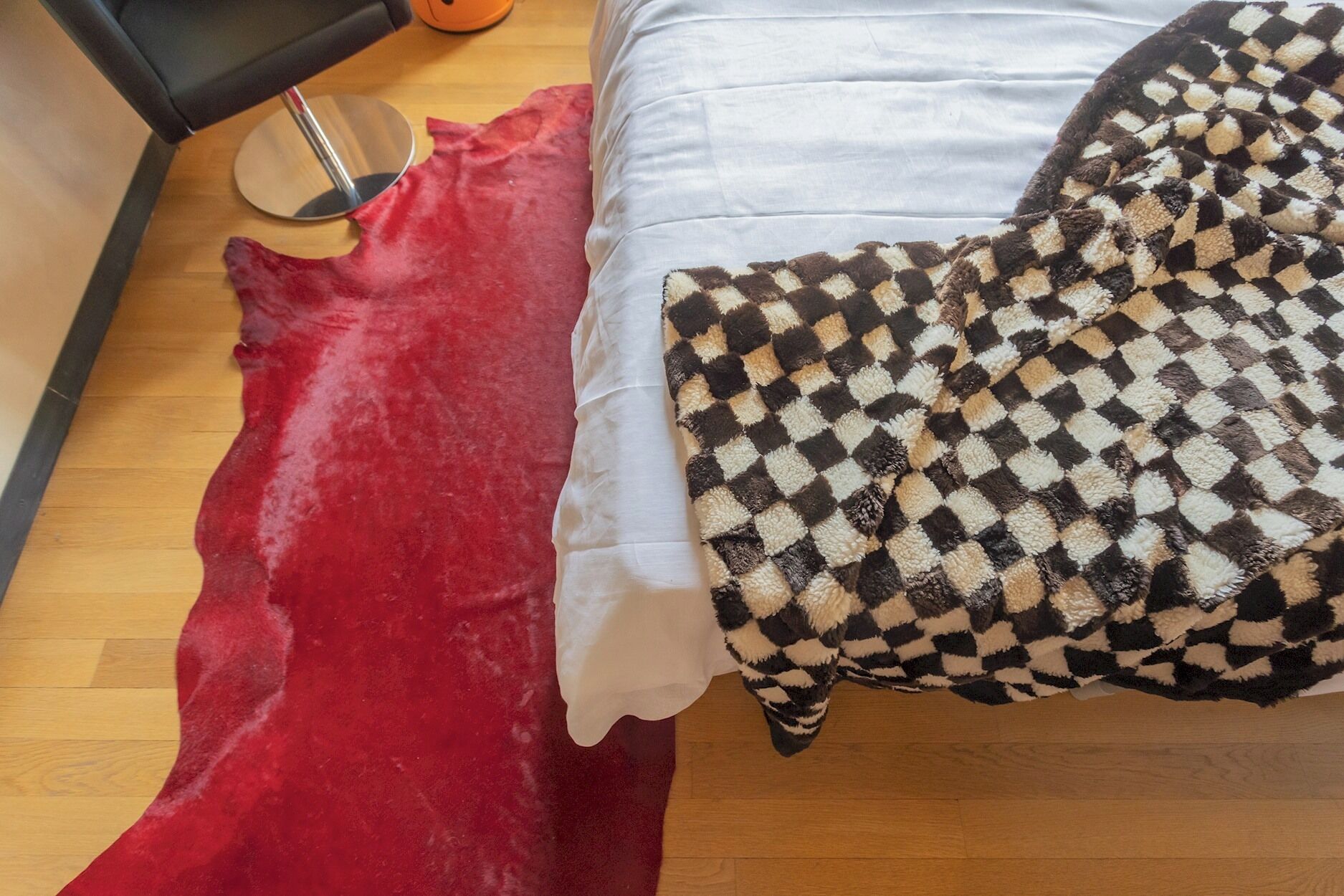 Una cama con sábana blanca y manta a cuadros blanco y negro.