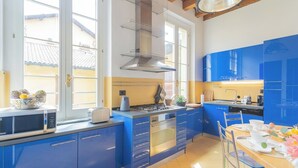 A modern kitchen with blue cabinets, a gas stove, and a built-in oven. - Night at the Museum Apartment by Rent all Como (Como)
