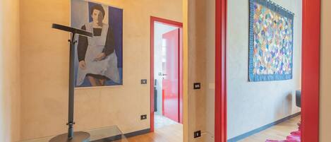 Un interior moderno con una vitrina de vidrio, un cuadro en la pared y un colcha colorida colgada en la puerta.