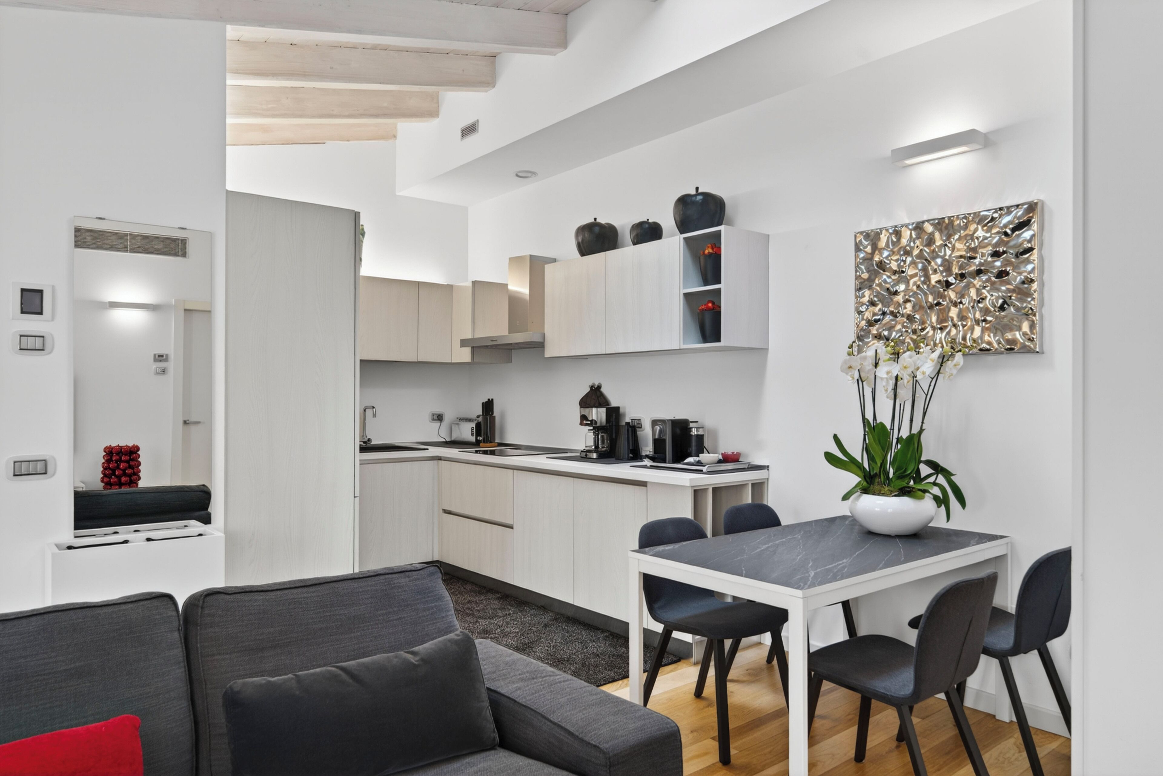 A modern kitchen with white cabinets, a dining table with chairs, and a staircase leading to another level.
