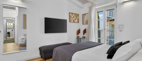 A modern bedroom with a bed, a bench, a TV, and artwork on the wall.