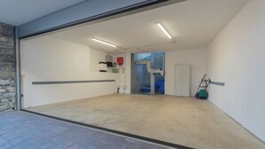Un vaste espace intérieur doté d’un sol en béton, d’un mur en pierre d’un côté et d’une porte donnant sur une autre pièce.
