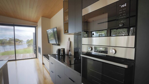 Una cocina moderna con un horno grande, un microondas y un televisor montado en la pared.