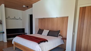 Un dormitorio moderno con una cama de madera, una alfombra gris y un cabecero de madera.