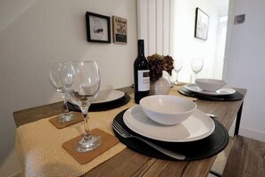 Une table à manger dressée avec des verres à vin, une bouteille de vin et des bols, le tout posé sur un set de table texturé.