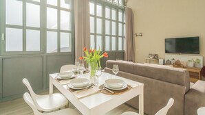 A dining area with a table set for four, a sofa, and a television on the wall. - Romantic Escape City Centre With Jacuzzi & Parking by Rent all Como (Como)