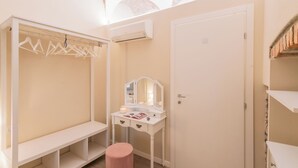 A room with a white vanity, a mirror, and a pink stool. There is a white wardrobe with a hanging rod and a door. - Romantic Escape City Centre With Jacuzzi & Parking by Rent all Como (Como)