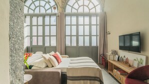 A hotel room with a large bed, a TV, a wooden side table, and a window with a view. - Romantic Escape City Centre With Jacuzzi & Parking by Rent all Como (Como)