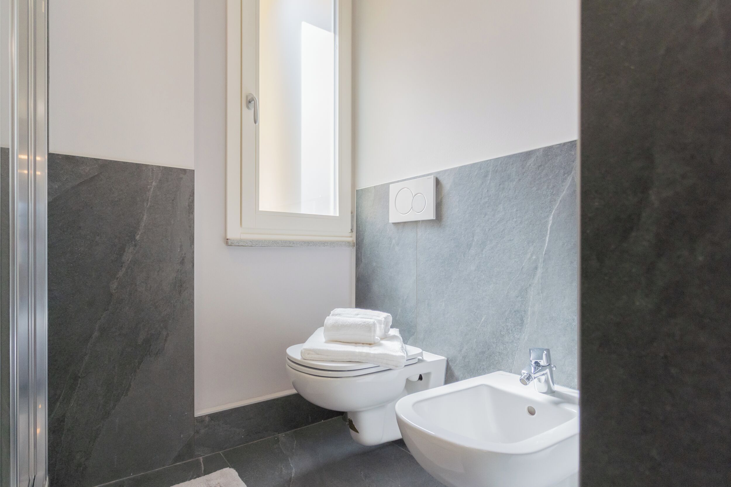 A modern bathroom with a toilet, bidet, and sink.