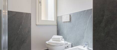 A modern bathroom with a toilet, bidet, and sink.