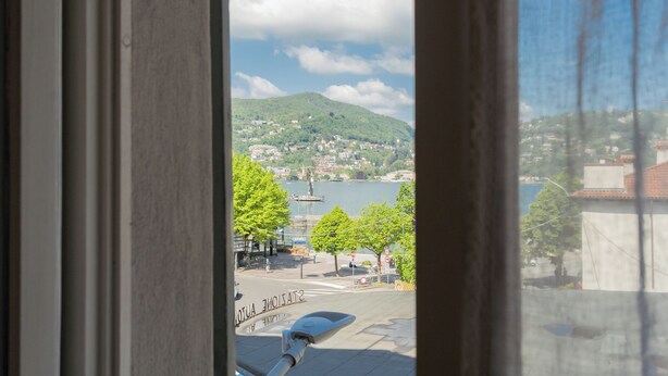 A view of a town with a hill, a body of water, and a statue in the distance. - Sant'Agostino Apartments by Rent all Como (Como)